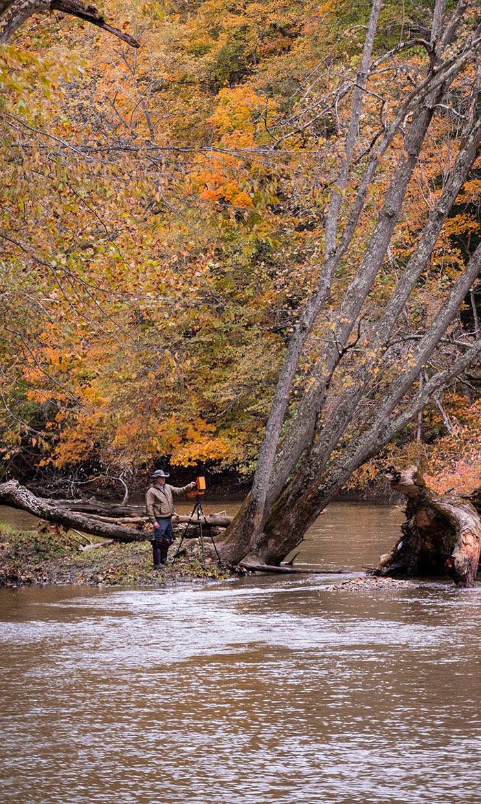 clint bova painting on the shore of a midwestern river in autumn